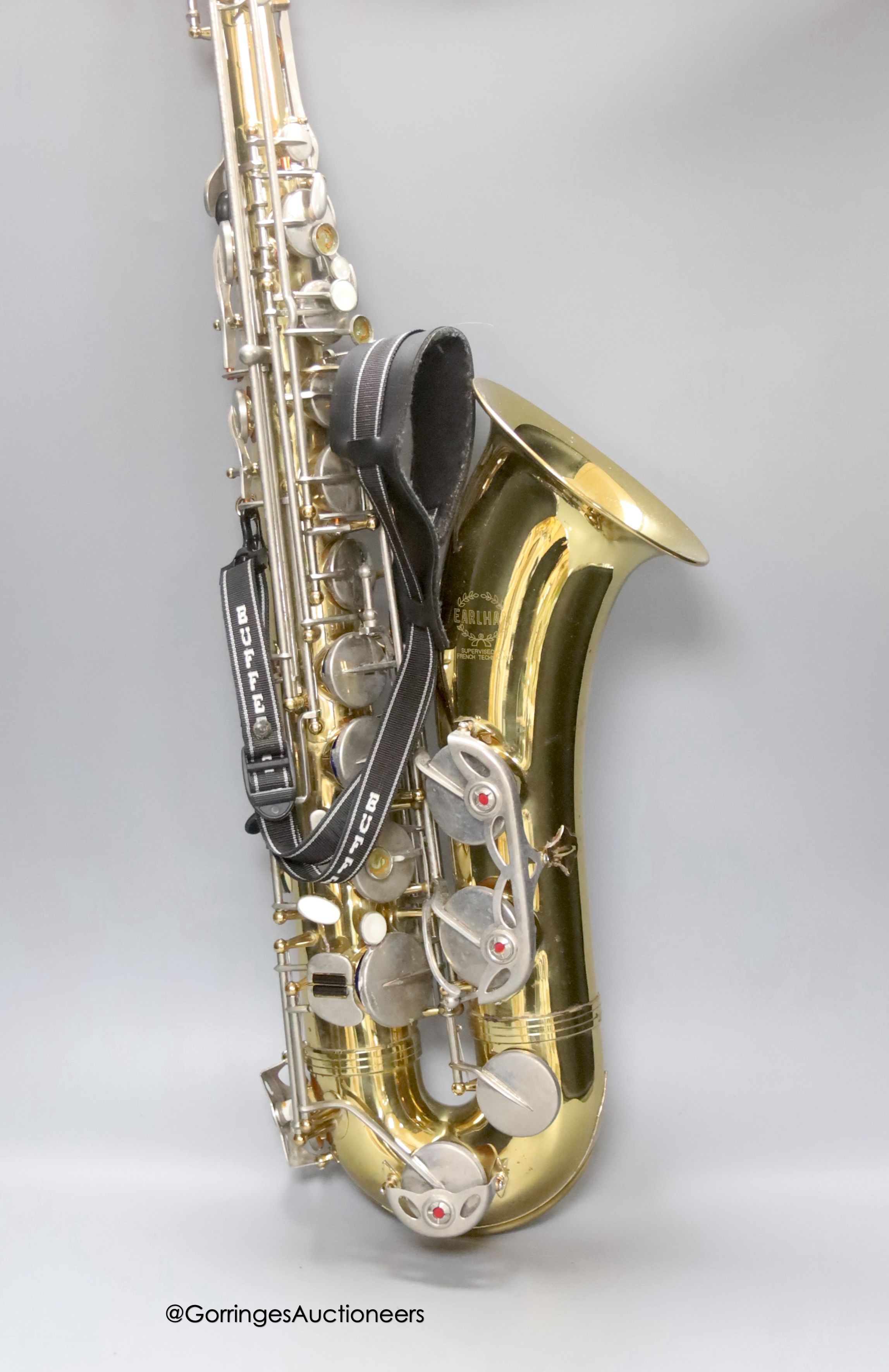 A cased Earlham brass saxophone and music sheets